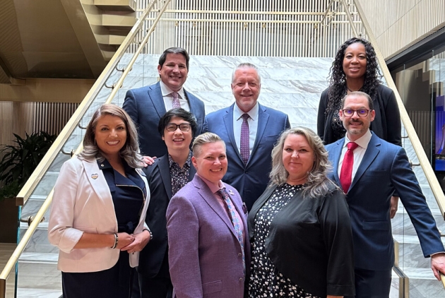 Board members of the LGBTQ Center standing on a staircase after presenting their accelerator plan